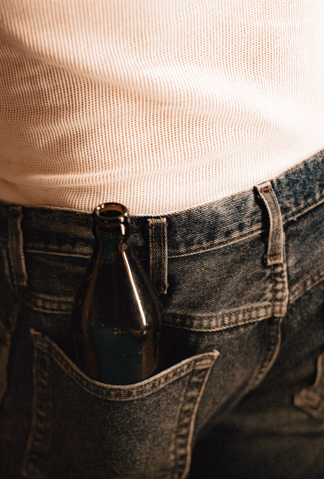 Ølflaske i baglommen på et par jeans